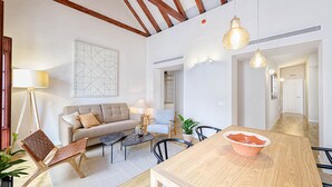 Una sala de estar moderna con un sofá, una mesa de centro y sillas, una mesa de comedor de madera y un cuadro abstracto grande.