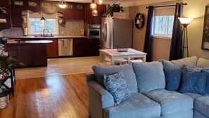 A modern kitchen with dark wood cabinets, stainless steel appliances, and a central island. - Charming rental within walking distance to public boat launch on Sage Lake! (Hale)