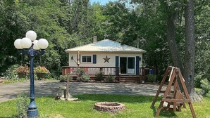 A house with a porch, a star on the door, and a swing set in the yard. - Charming rental within walking distance to public boat launch on Sage Lake! (Hale)