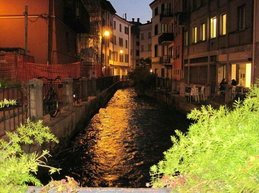Un étroit canal bordé d’immeubles dotés de balcons et d’espaces de restauration en plein air, ce qui laisse supposer qu’il se trouve au bord d’une rivière.