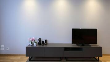 Ein modernes, dunkel gefärbtes Unterhaltungseinrichtung mit einem Flachbildfernseher, einer kleinen Vase mit Blumen und einer Fernbedienung.