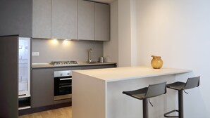 A modern kitchen with a central island, bar stools, and built-in appliances. - Brand new apartment in the heart of Udine (Udine)