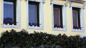 A building facade with three windows, each with a stone frame and potted plants. - Brand new apartment in the heart of Udine (Udine)