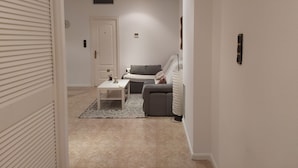 A modern living room with a grey sofa, a white coffee table, and a patterned rug.