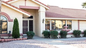 A two-story house with a red-tiled roof, a front porch, and a small fountain. - Private oasis to relax in the sun. (Sun City West)