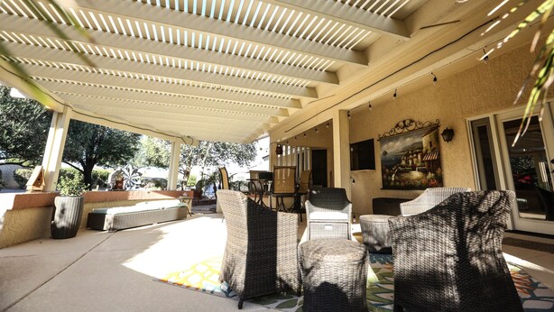 An outdoor patio with wicker furniture, a covered area with slatted ceiling, and a mural on the wall. - Private oasis to relax in the sun. (Sun City West)
