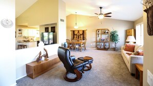 A spacious living room with a leather recliner, a wooden coffee table, and a dining area with a chandelier. - Private oasis to relax in the sun. (Sun City West)