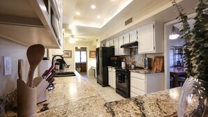A kitchen with granite countertops, white cabinets, a black refrigerator, and a ceiling fan. - Private oasis to relax in the sun. (Sun City West)