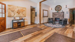 A lobby with a wooden floor, a world map on the wall, a stone fireplace, leather chairs, and a reception desk.