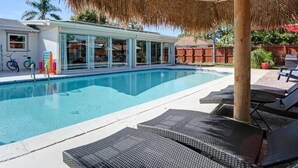 A swimming pool with lounge chairs and a thatched umbrella. - 3/2 Heated Pool House Walking Distance to Beach (Naples)