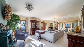 A spacious living area with a large sofa, a dining table, and a kitchen area with a view. - Sunset Mansion (Argostoli)