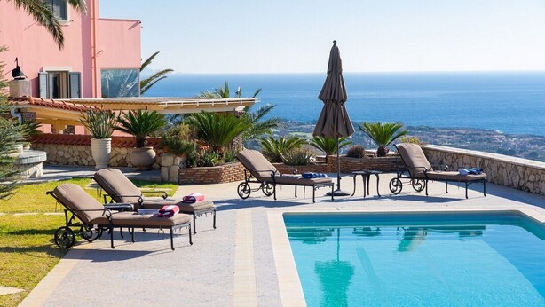 A pool area with lounge chairs and a view of the sea. - Sunset Mansion (Argostoli)