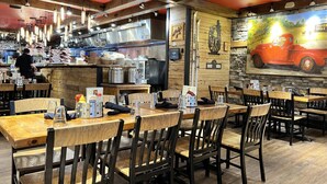 A restaurant interior with wooden tables and chairs, a kitchen area, and a mural of a vintage car. - ML148 Corner unit w/ views & fireplace connects to ML150 (rented separately) (Snowshoe)