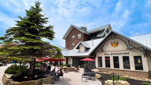 A brick building with a sign reading "The Junction" and outdoor seating with umbrellas. - ML148 Corner unit w/ views & fireplace connects to ML150 (rented separately) (Snowshoe)