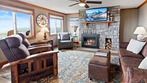 A cozy living room with a stone fireplace, comfortable seating, and a large window offering a scenic view. - ML148 Corner unit w/ views & fireplace connects to ML150 (rented separately) (Snowshoe)