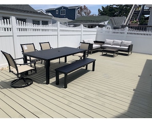 An outdoor deck with a table and chairs, a bench, and a sofa.