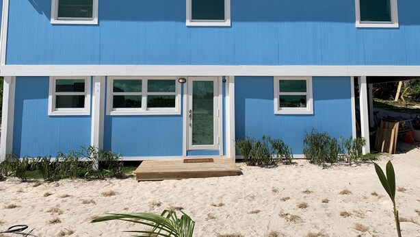A two-story blue house with white trim, a front door, and a small porch.