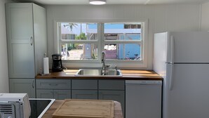 A compact kitchen with a sink, a wooden countertop, and a refrigerator.