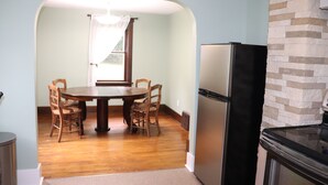Un comedor con una mesa y sillas de madera, un refrigerador y una chimenea de piedra.