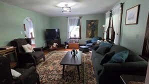 Una sala de estar con un sofá, sillones, una mesa de centro, un televisor y una alfombra.