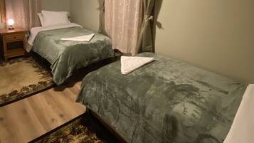 Une chambre avec deux lits, une table de chevet, une lampe et un tapis à motifs.