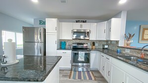 A modern kitchen with white cabinets, stainless steel appliances, a granite countertop, and a "WELCOME" sign on the wall. - Island Tyme- Canal Waterfront Paradise with Sunset View! (Freeport)
