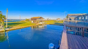 A waterfront property with a wooden deck, a pool, and a view of the ocean and golf course. - Island Tyme- Canal Waterfront Paradise with Sunset View! (Freeport)