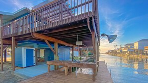 A wooden deck with a pool, a covered area with a table and chairs, and a view of the water. - Island Tyme- Canal Waterfront Paradise with Sunset View! (Freeport)