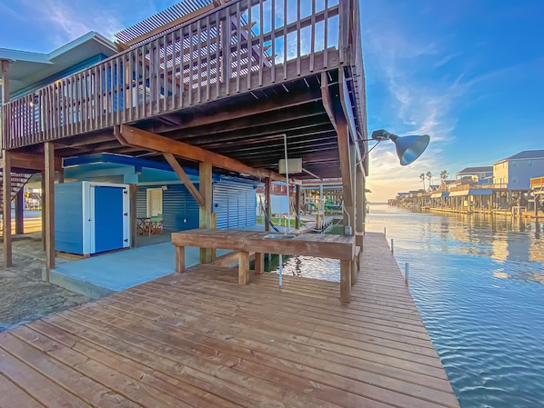 A wooden deck with a pool, a covered area with a table and chairs, and a view of the water. - Island Tyme- Canal Waterfront Paradise with Sunset View! (Freeport)