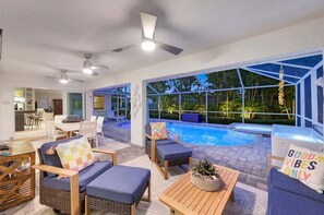 A modern indoor pool area with seating, a dining area, and a view of the outdoors. - Seaclusion -Luxury Saltwater Pool/Spa/Cold Plunge/Minigolf/ Near Beach (Naples)