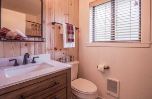 A bathroom with a wooden vanity, a sink, a toilet, and a window with blinds. - Modern Cabin w/ EV Car Charger and Pool Access (Dorrington)