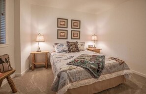A bedroom with a bed, two nightstands, a wooden bench, and a wall with four framed pictures. - Modern Cabin w/ EV Car Charger and Pool Access (Dorrington)
