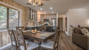 A modern kitchen with wooden cabinets, a dining table, and a sofa. - Modern Cabin w/ EV Car Charger and Pool Access (Dorrington)