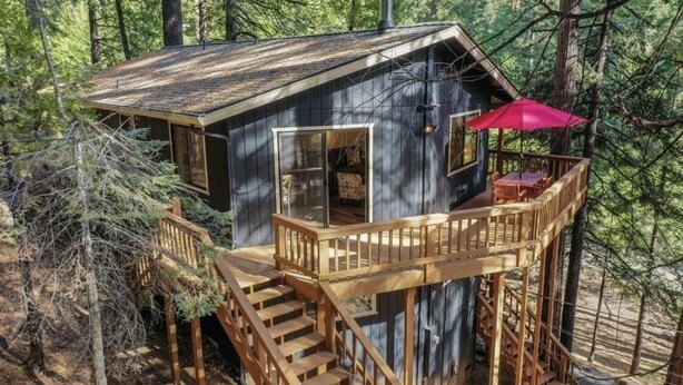 A cabin with a deck, stairs, and a red umbrella. - Modern Cabin w/ EV Car Charger and Pool Access (Dorrington)