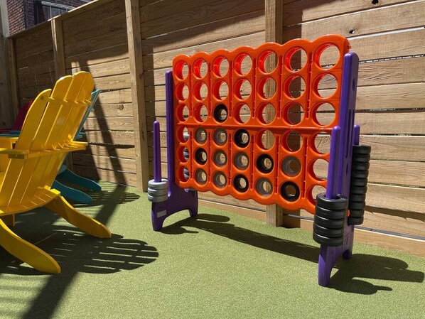 Een speelplaats met een houten hek, een gele glijbaan en een klimconstructie in paars en oranje.