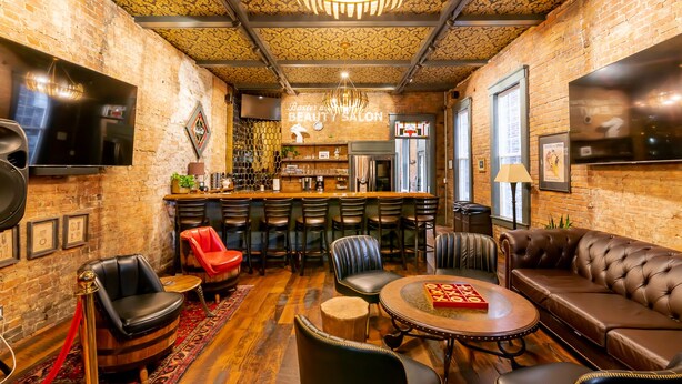 A cozy bar area with a brick wall, a wooden bar counter, and leather seating.
