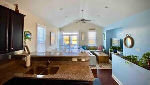 A spacious kitchen with granite countertops, a double sink, and a ceiling fan. - Your family will be close to everything when you stay at this centrally-located beach oasis (Surf City)