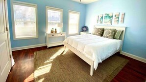 A bedroom with a bed, a nightstand, a ceiling fan, and two windows with blinds. - Your family will be close to everything when you stay at this centrally-located beach oasis (Surf City)
