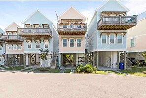 Three-story townhouses with a central entrance and covered porch, each featuring a balcony on the upper floor.