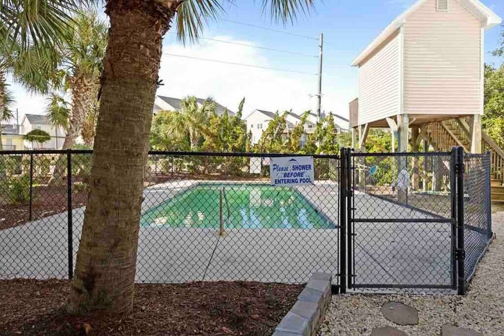 A fenced pool area with a sign instructing to shower before entering.