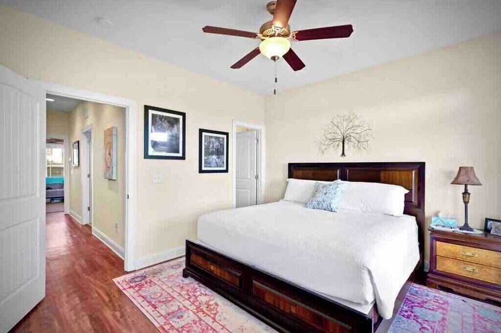 Une chambre avec un lit en bois, un ventilateur de plafond et une table de chevet avec une lampe.