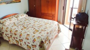 Een slaapkamer met een bed, een kledingkast, een schilderij aan de muur en een deur naar een andere kamer.