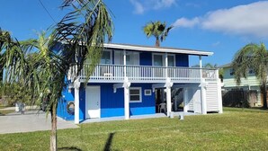 Une maison à deux étages, avec une façade bleue et des balustrades de balcon blanches.