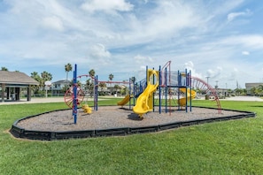 Un parque infantil con un tobogán amarillo y una estructura de escalada de color rojo y azul.