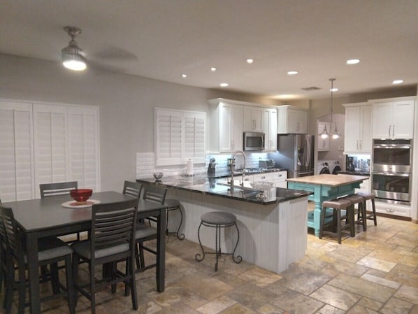 A modern kitchen with white cabinets, a central island, and stainless steel appliances.