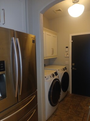 A compact kitchen with a stainless steel refrigerator, a washing machine, and a microwave. - Serene Golf Course Suite with Private Bedroom, Bath + Heated Pool & Spa. (Mesa)