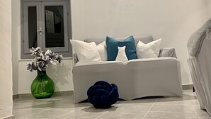 Een moderne woonkamer met een bank, een blauw decoratief object en een groene vaas met bloemen.