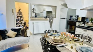 Een moderne woonkamer met een eethoek, een kerstboom en een keuken met een koelkast en oven.
