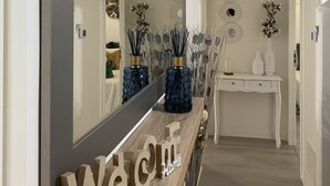 Een modern interieur met een houten receptiebalie, een grote spiegel en decoratieve vazen.
