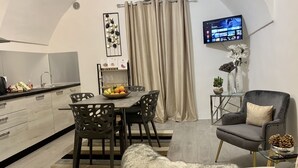 Een moderne keuken met een eetgedeelte, een flatscreen televisie aan de muur en een gezellig zithoekje met een zachte, pluizige deken.